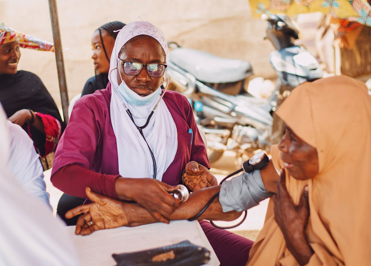Outdoor portrait of healthcare professional attending to a patient, promoting community wellness in Kaduna, Nigeria.